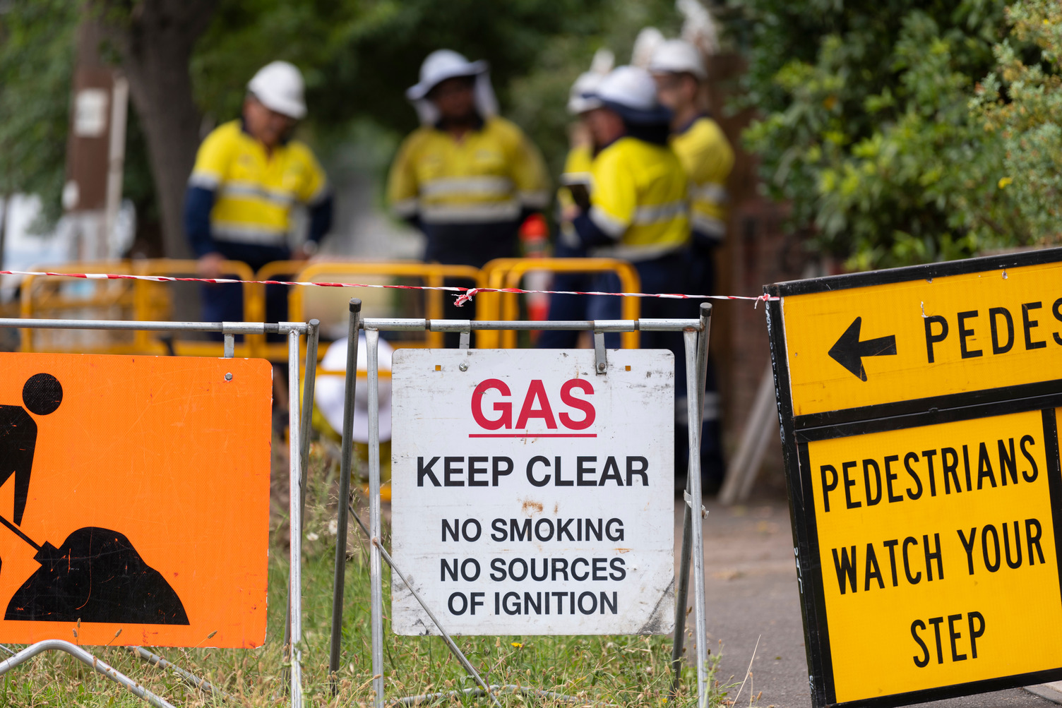 A group of gas workers outside behind constructions signs