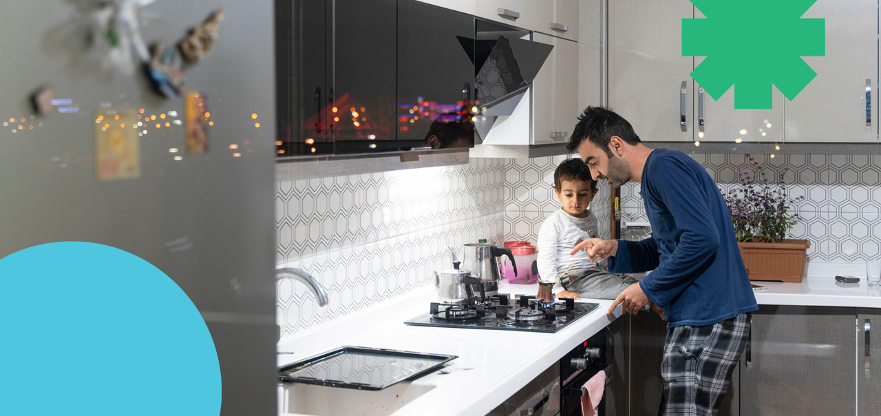 Father showing stove to son sitting on countertop