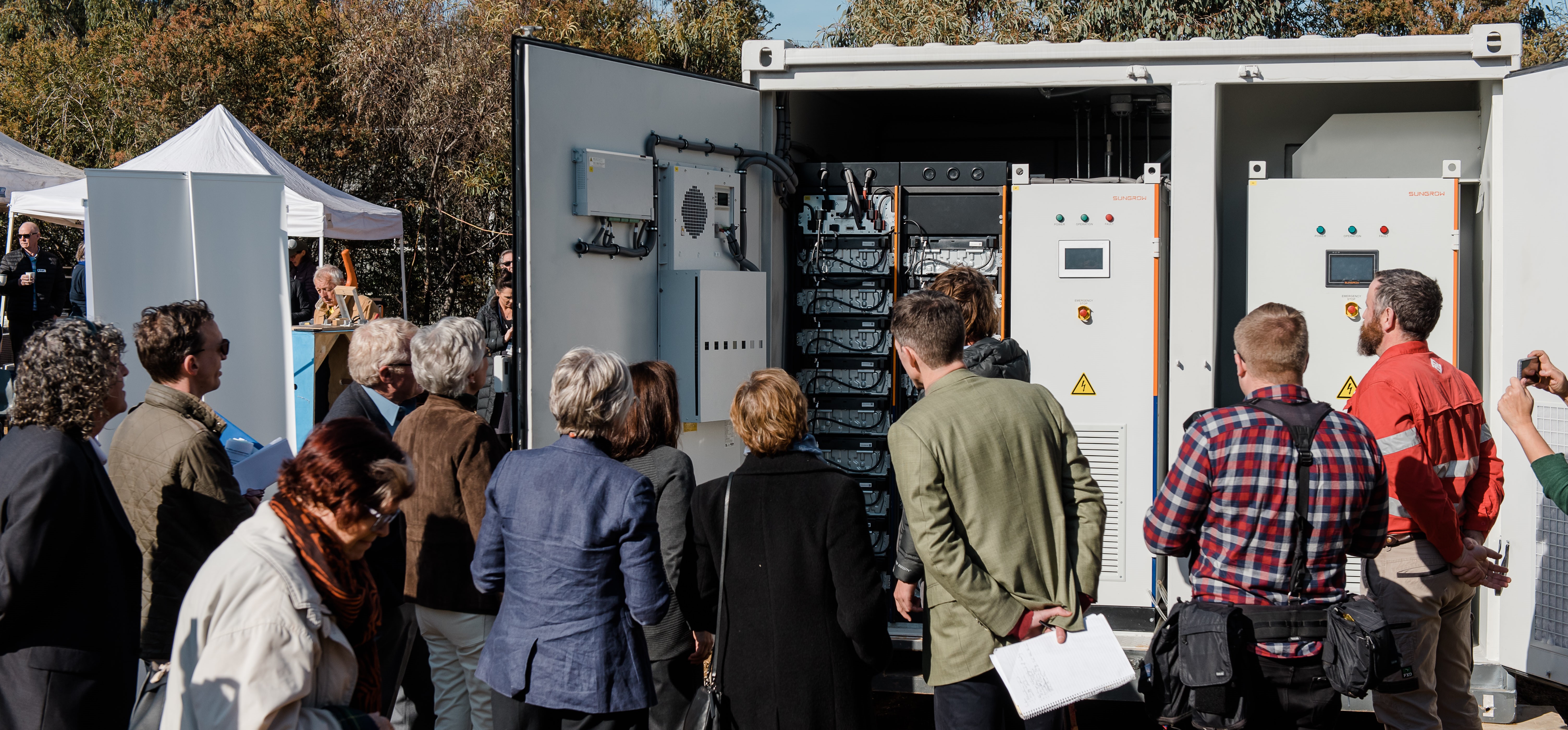 A group of people outside viewing a large battery